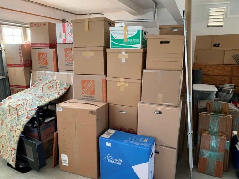 Stacked cardboard moving boxes and furniture in a residential garage