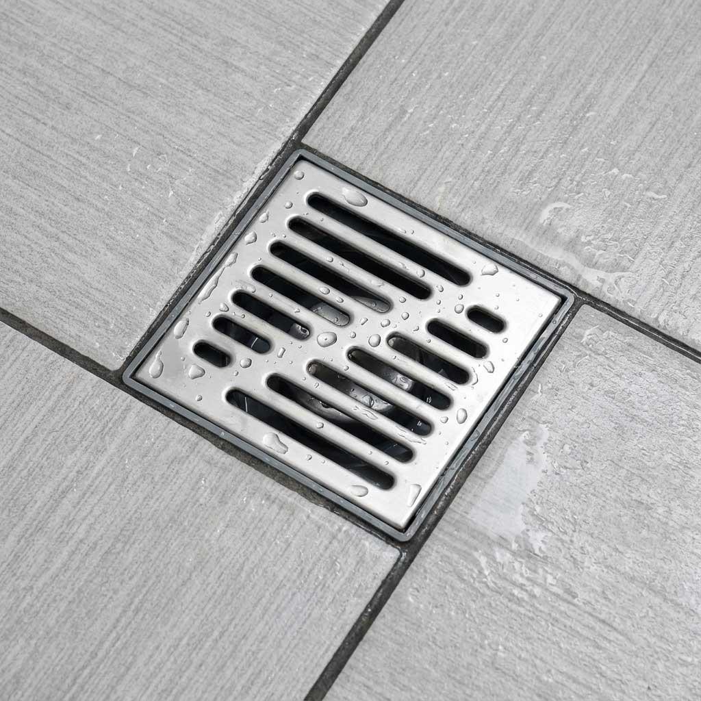 A stainless steel floor drain grate set into tiled flooring